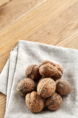 A stack of walnuts piled together and on rustic wooden background, shallow depth of field, selective focus, vertical