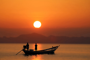Silhouette of the long tail boat with red sunset sky.
