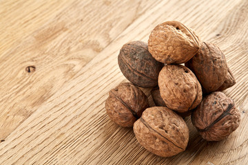 A stack of walnuts piled together and on rustic wooden background, shallow depth of field, selective focus