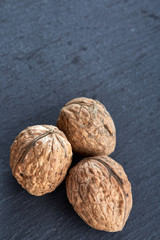 A stack of walnuts piled together and isolated on dark background, shallow depth of field, selective focus, vertical