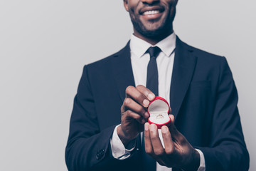 Will you marry me? Cropped close up photo of happy cheerful excited man dressed in smart suit holding a red box with engaging ting, isolated on grey background