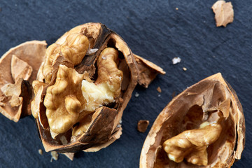 Top view close-up shot of cracked walnuts on dark background, shallow depth of field, macro