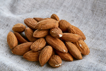 Heap of almond nuts on light tablecloth, close-up, shallow depth of field, selective focus, macro