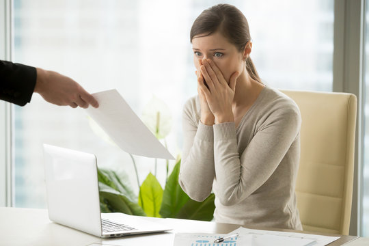 Young woman shocked when receiving dismissal notification from boss. Upset female employee worrying because of mistakes in calculations. Office worker can not believe in breaking employment contract
