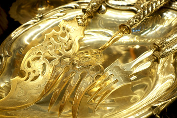 Decorative golden forks in the form of a trident on a golden tray.