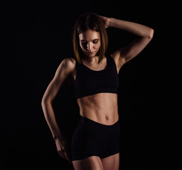Fototapeta premium Sporty muscular female doing workout with dumbbells isolated on black background. Athletic young woman do a fitness workout with weights.
