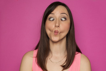 Young funny woman making silly faces on pink background - obrazy, fototapety, plakaty