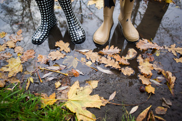Girl wearing rain boots standing in a puddle on warm summer day