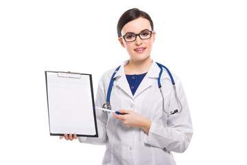 Young woman doctor with stethoscope holding pen in her hand showing on clipboard in white uniform on white background