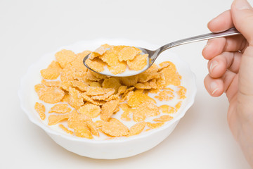 In the morning woman eating corn flakes with spoon. Corn flakes with milk in the white bowl in the kitchen at home. Healthy breakfast concept. © fotoduets