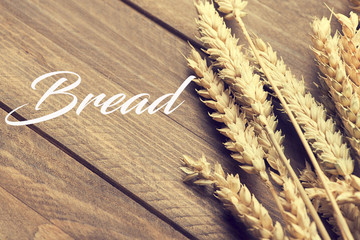 The word bread written together wheat flower background on wooden table. Food