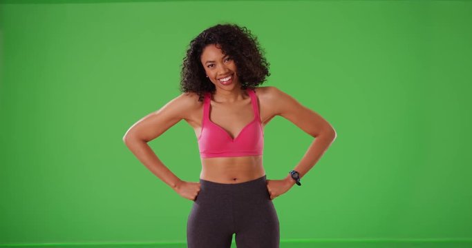 Athletic black woman trainer smiling and laughing in active wear on green screen. Happy young female fitness instructor smiles and laughs on greenscreen. 4k
