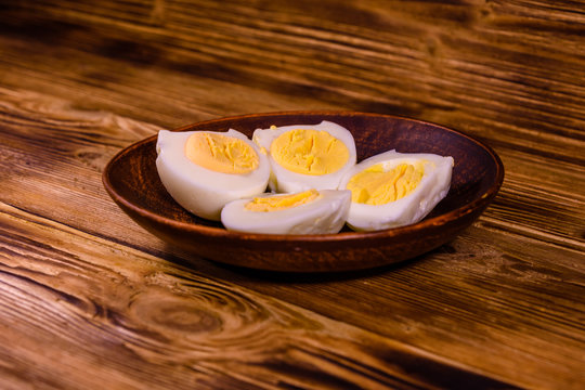 Ceramic plate with peeled boiled eggs on wooden table