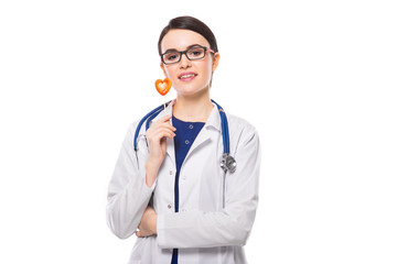 Fototapeta premium Young woman doctor with stethoscope holding heart in her hands in white uniform on white background