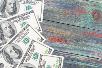 Money on a colored wooden background. Stack of one hundred dollars bills on wooden desk