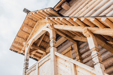 Part of the facade of a wooden house in ancient style. Beautiful wooden veranda on the second floor...