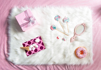 Top view rosy present, sweets, marshmallow, copybook and mirror situating on floor. Fashion concept