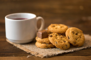 White cup of tea and cookies on dark wooden background