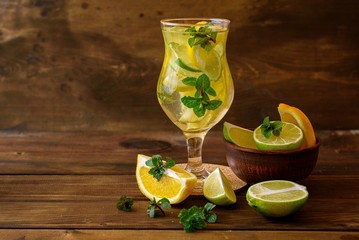 Water with lime, lemon and mint leaves on a dark wooden background