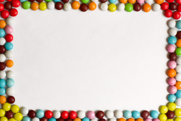 Round chocolate Bonbons covered with colored glaze on white background. Top view. Copy space.
