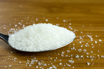 white sugar pile spoon wooden table. copy space, close up, selective focus