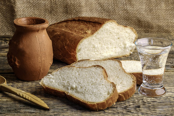 white bread and clay pot on wooden table, rustic Breakfast with a glass of vodka