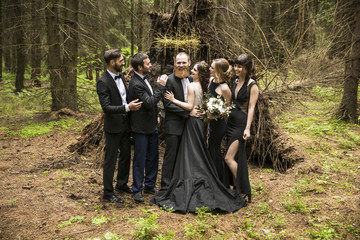 portrait of the couple and the witnesses in the background of a hut in the woods