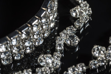 Silver bracelet and necklace with diamonds on black background close-up