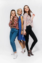 Fototapeta premium Three happy girls dressed in casual style pose in the studio