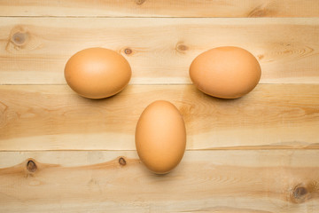 Three chicken eggs lie on a wooden board