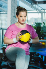 overweight woman training with medicine ball at gym