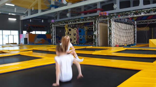 Daughter Bouncing On Trampoline While Her Mother Watch for Safety.