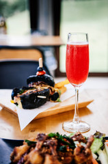 Refreshing red cocktail punch with in sparkling wine glass on dinner table with foods, vertical shot