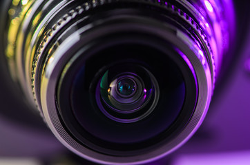 The lens of the camera with lights of yellow and purple. Horizontal photo.