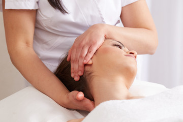 Fototapeta na wymiar Female Enjoying Relaxing face Massage In Cosmetology Spa Center