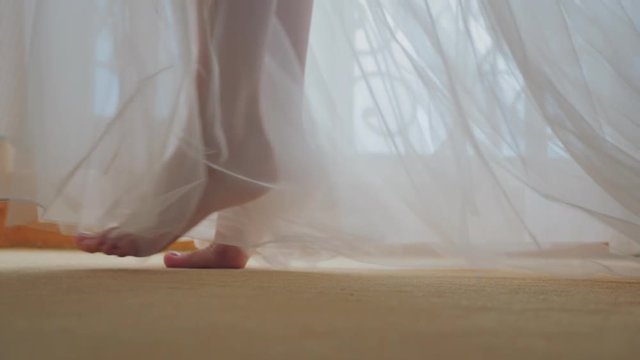 Slow motion close-up footage of feet get out of bed and hit the floor.