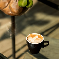 Hot Latte art coffee black cup on Wooden table and sunlight