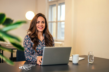 Woman in bright modern office working on laptop.