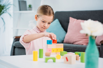 portrait of kid playing with colorful blocks in living room at home