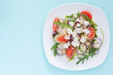 Fresh spring salad with cucumber, tomato, cheese and arugula isolated on a white plate 