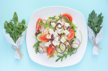 Fresh spring salad with cucumber, tomato, cheese and arugula isolated on a white plate 