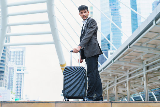Business man walking at outdoors with luggage in the routine of working with determination and confidence. concept of business trip travel and transportation.