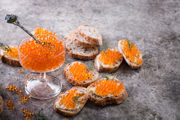 Delicious bright red fresh snack red caviar on a wooden background. Silver spoon with caviar. Expensive luxury delicacy seafood.