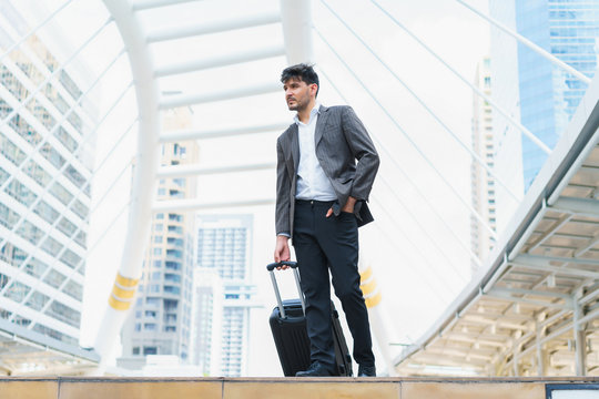 Business man walking at outdoors with luggage in the routine of working with determination and confidence. concept of business trip travel and transportation.