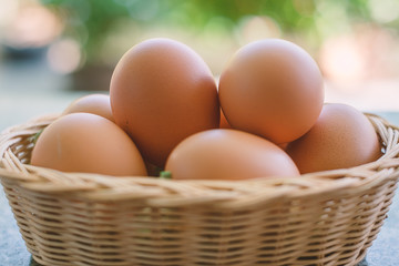 Eggs in the wicker basket on blurred natural green background
