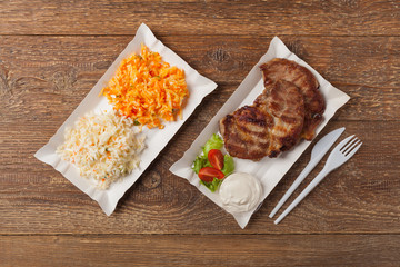 Grilled pork neck served on paper trays.