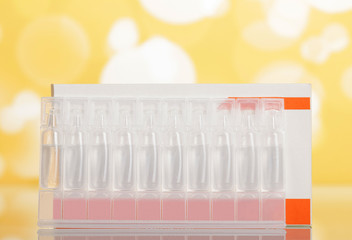 Carton box and ampoules of drug solution on yellow background