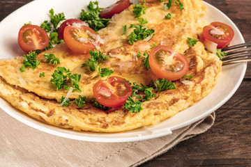 Closeup of omelette with parsley and cherry tomatoes