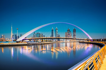 Fototapeta premium Dubaj, Zjednoczone Emiraty Arabskie - luty 2018: Kolorowy zachód słońca nad drapaczami chmur w centrum Dubaju i nowo wybudowanym mostem tolerancji, patrząc z kanału wodnego w Dubaju.
