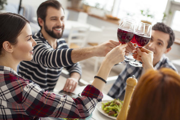 Best day ever. Attractive delighted old best friends sitting together at the table and drinking wine and eating and clanging glasses